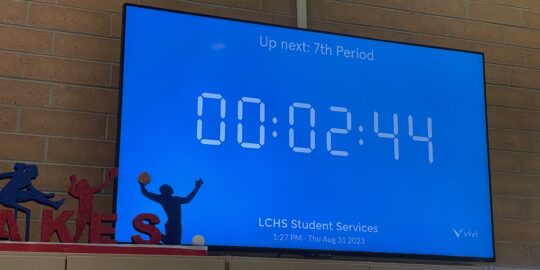 A flat panel display shows a countdown timer on the wall of a school hallway, helping students know how much more time they have before the bell rings.