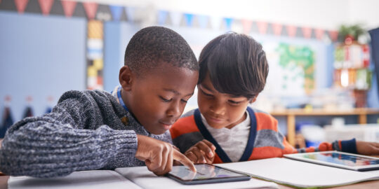 Students in classroom doing research for work, test or exam. Technology, education and boy children friends working on project or assignment together with mobile on campus