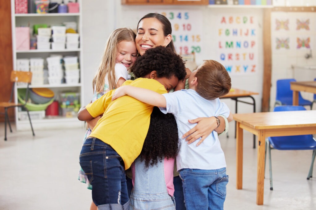 Teacher is hugged by students in a classroom