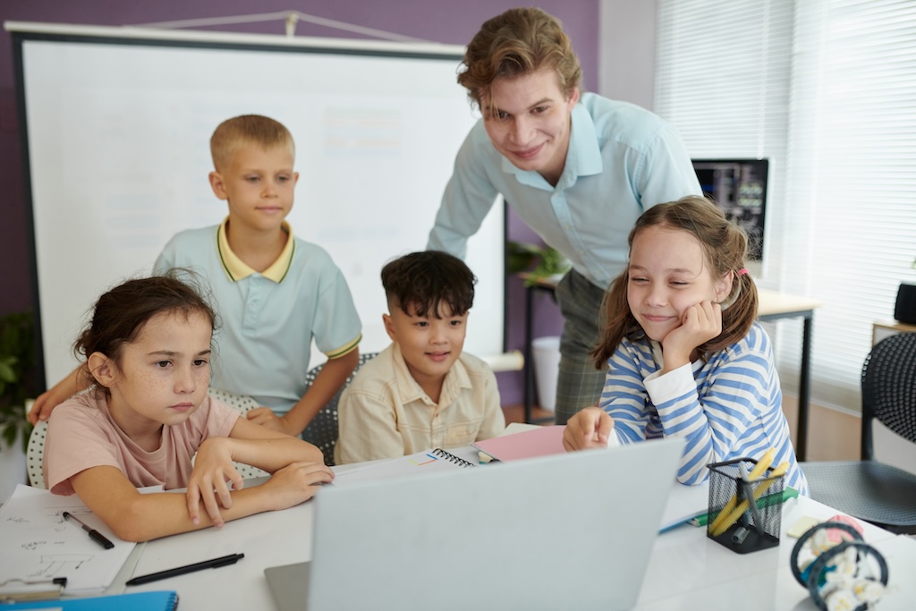 Teacher's Guide to Inspiring Engagement: Tips & Activities 1 A group of elementary students looking at a laptop with a teacher looking on