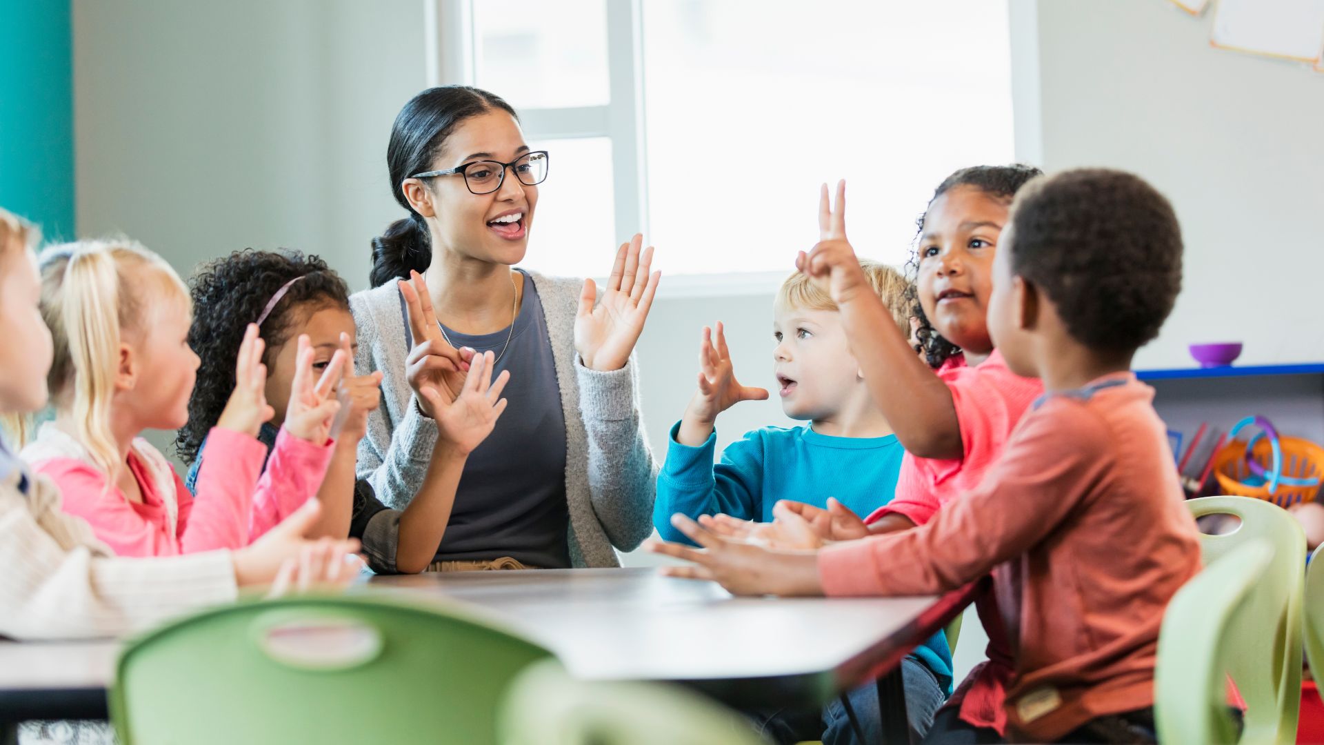 An early career teacher standing in front of an interactive classroom display interacting with students